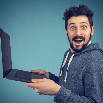 man holding a laptop looking happy